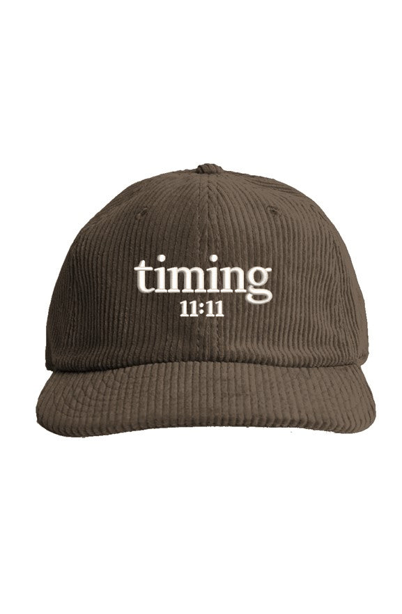 Front view of a brown corduroy hat featuring the embroidered "timing 11:11" logo in ivory