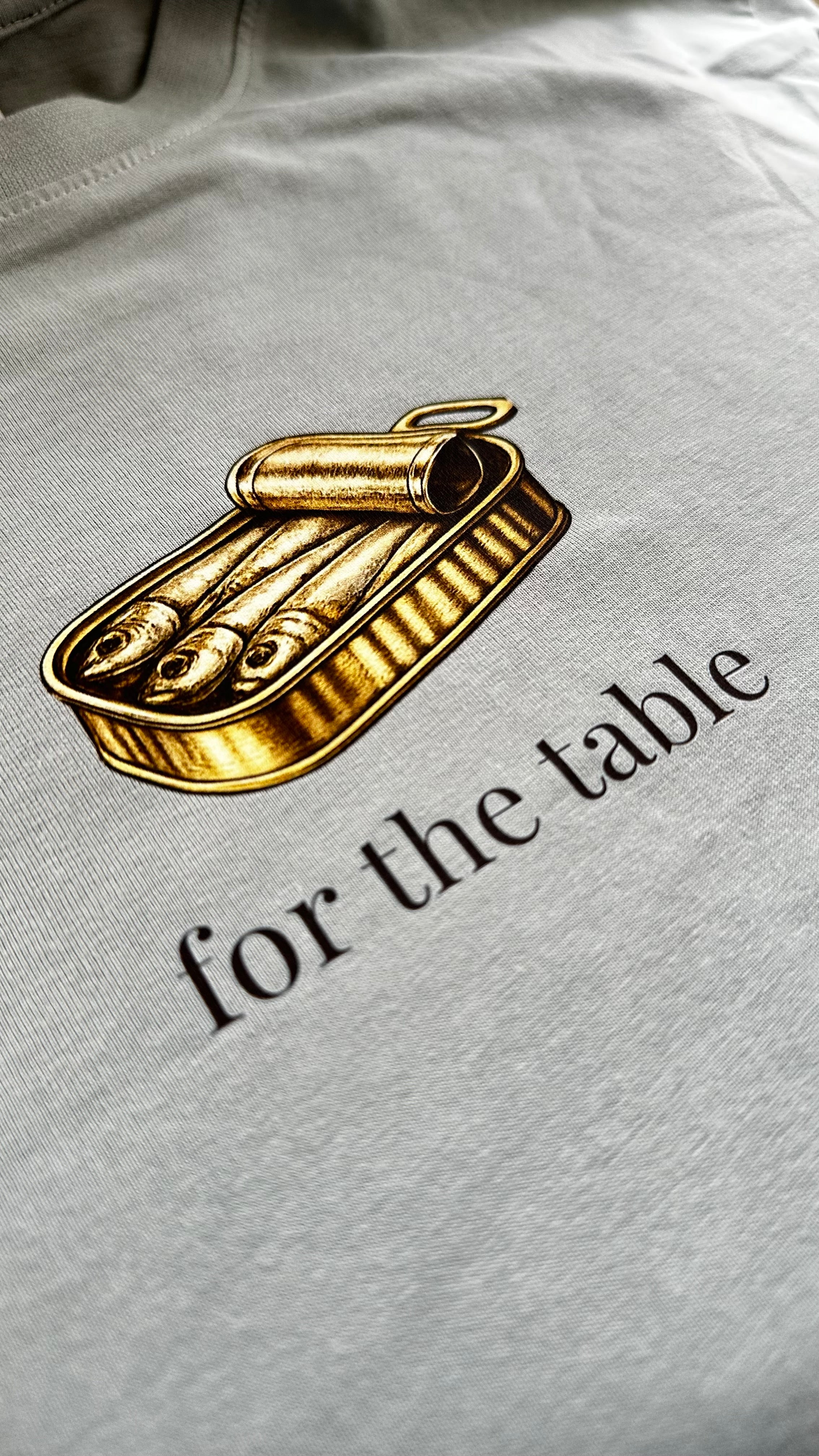 Close-up of the sardine tin graphic and "for the table" text on a Sea Glass t-shirt.