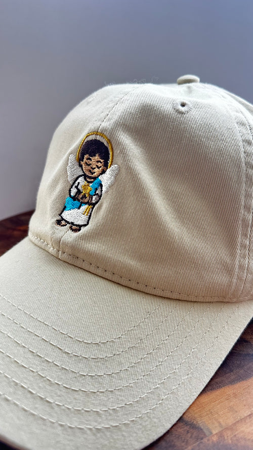 Angled view of a beige dad hat featuring the Light Guardian angel embroidery.