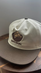 Angled view of a cream and brown two-tone cap with embroidered basket of pandesal and "PANDESAL" text.