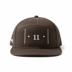 front view of a brown cap with white embroidered Passage Mark featuring vertical bars, dots, and the number 11