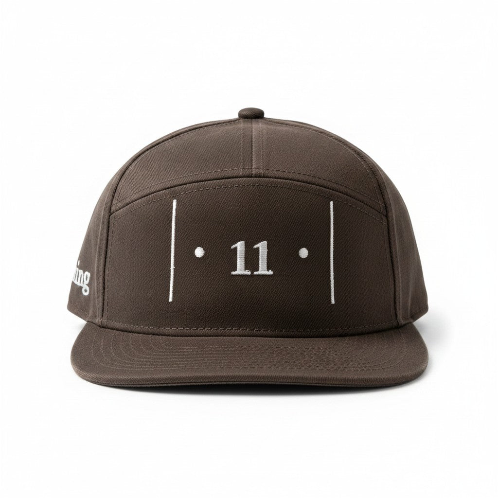 front view of a brown cap with white embroidered Passage Mark featuring vertical bars, dots, and the number 11