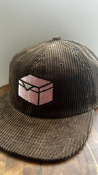 Brown corduroy hat embroidered with a pink donut box icon on a wooden surface.