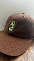 Angled view of a brown dad hat featuring embroidered Rose Protector holding a red rose.