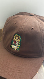 Angled front view of a brown dad hat featuring embroidered Rose Protector holding a red rose.