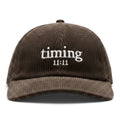Front view of a brown corduroy hat featuring the embroidered "timing 11:11" logo in ivory