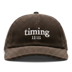 Front view of a brown corduroy hat featuring the embroidered "timing 11:11" logo in ivory
