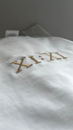 Close-up of the XI:XI embroidery on a white editorial t-shirt.